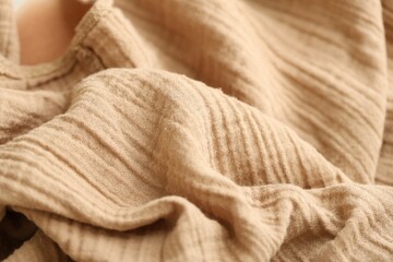 Texture of crumpled linen fabric under natural light in peach fuzz color