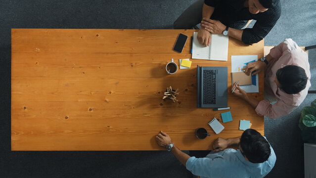Top down aerial view of business team looking at financial graph while shaking hands for making agreement. Diverse people planning marketing strategy at table with stock market chart. Convocation.