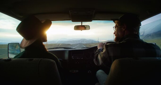 Man and woman driving an old van along a scenic road during sunset, soaking in the breathtaking landscape and sharing moments of joy and adventure together