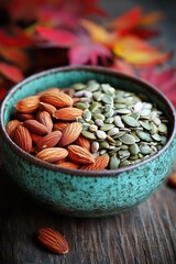 Fototapeta premium Bowl of Almonds and Pumpkin Seeds with Autumn Leaves on Rustic Wooden Table