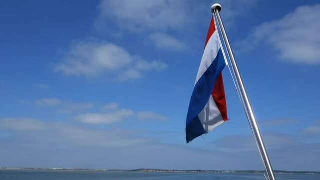 Wadden Sea Friesland The Netherlands Dutch flag waving from the stern of a ship