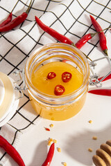 Hot honey in glass jar. Hot sauce recipe. Slices of peppers in honey. Vertical