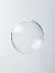 Transparent soap bubble floating against a soft grey background