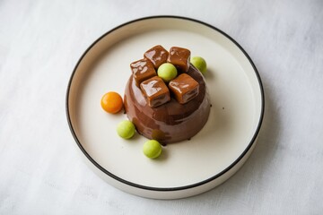 A decadent chocolate mousse dessert, adorned with caramel cubes and colorful candies.