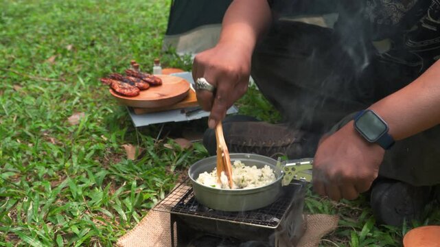 Close up of the activity of an Asian male adventurer cooking lime leaf rice using charcoal and wood. The bushcraft concept makes lime leaf rice with simple equipment in the lush wilderness