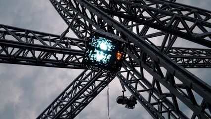 Technicians work at dusk on stage rigging and lighting setup for an outdoor event