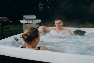 A modern hot tub with joyful people inside. An idea for spa, relaxation and enjoyment of life.