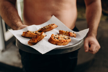 A man in the role of a waiter holds canapes on a tray for people to eat in the jacuzzi.