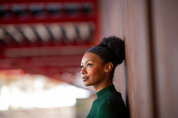 Woman leaning on a wall looking ahead in a vibrant urban setting