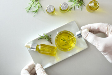 Hands in laboratory manipulating pipette with bottles with rosemary extract
