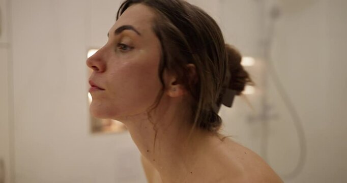 Close-up of a brunette girl applying moisturizing ointment and doing a facial massage after getting out of the shower in the bathroom