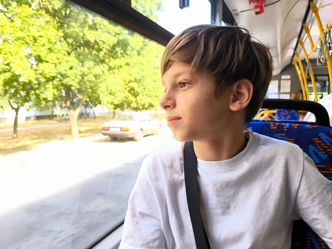 Happy boy rides the bus. A happy boy looks out the window on a school bus - Powered by Adobe