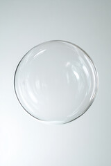 Transparent soap bubble with subtle reflections on light gray background