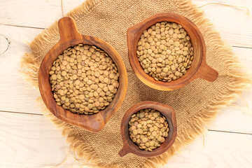 Lentil seeds in wooden cups on a wooden table, close-up, top view.