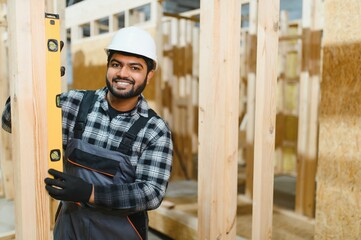Modern modular house. Indian worker works on the construction of a wooden house