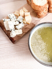 Green soup served with assorted cheeses and fresh bread on a wooden table