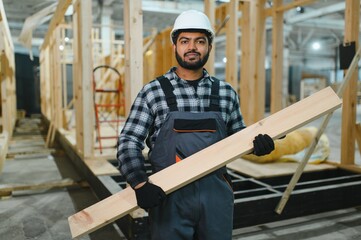 Modern modular house. Indian worker works on the construction of a wooden house