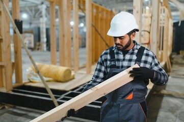 Modern modular house. Indian worker works on the construction of a wooden house