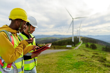 Engineer and operator using digital tablet and walkie talkie, inspecting a wind turbine park