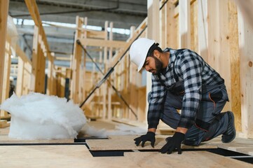 Modern modular house. Indian worker works on the construction of a wooden house