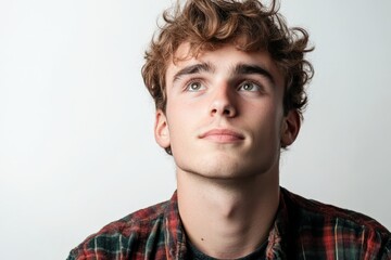 Obraz premium Thoughtful Young Man with Curly Hair Looking Upwards in a Studio Setting