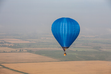 Blue hot air balloon flying above the English countryside