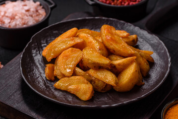 Baked potato wedges with cheese and herbs on a dark background