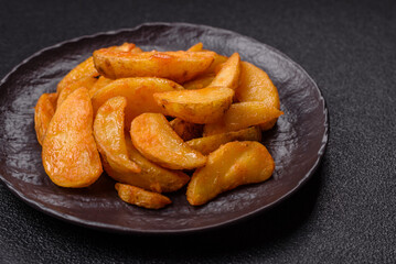 Baked potato wedges with cheese and herbs on a dark background