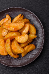 Baked potato wedges with cheese and herbs on a dark background