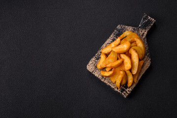 Baked potato wedges with cheese and herbs on a dark background