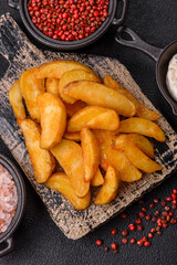 Baked potato wedges with cheese and herbs on a dark background
