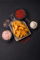 Baked potato wedges with cheese and herbs on a dark background