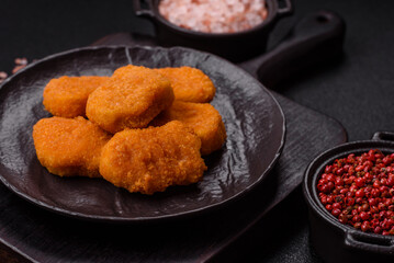 Delicious fresh crispy chicken nuggets on a dark concrete background