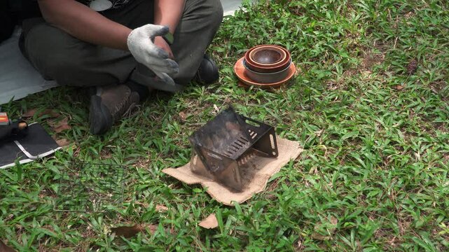 Close up of the activity of an Asian male adventurer cooking grilled shrimp using charcoal and wood. The bushcraft concept makes grilled shrimp with simple equipment in the lush wilderness