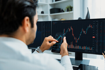 Trader businessman searching on smartphone, analyzing in dynamic stock exchange investment screen on pc with invest highest profitable financial technology market at modern home office. Surmise.
