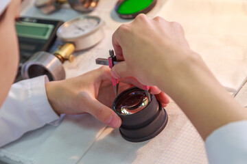 An engineer assembles a camera lens by hand.