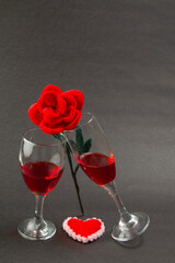 Romantic Valentine's Day wine glass with a rose and red heart shape on a table with a black background