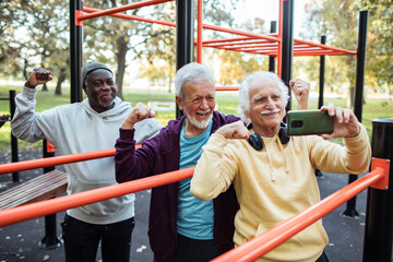 Senior men flexing muscles at outdoor park gym
