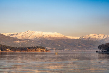 Snow-Capped Peaks Watch Over Ioannina Lake in Epirus, Greece. Reflective waters