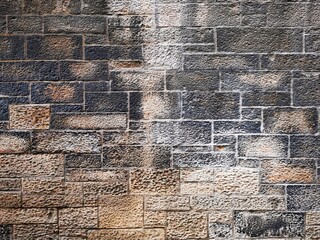 Background: Uneven old wall with different colored patched clinker bricks. Closeup. Walls of...