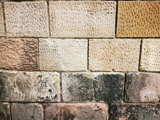 Background: Uneven old wall with different colored patched clinker bricks. Closeup. Walls of...