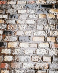 Background: Uneven old wall with different colored patched clinker bricks. Closeup. Walls of...