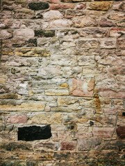 Background: Uneven old wall with different colored patched clinker bricks. Closeup. Walls of...