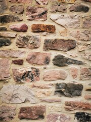Background: Uneven old wall with different colored patched clinker bricks. Closeup. Walls of...