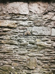 Background: Uneven old wall with different colored patched clinker bricks. Closeup. Walls of...