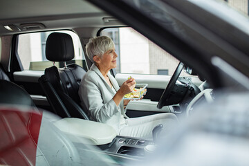 Senior businesswoman eating healthy lunch in car
