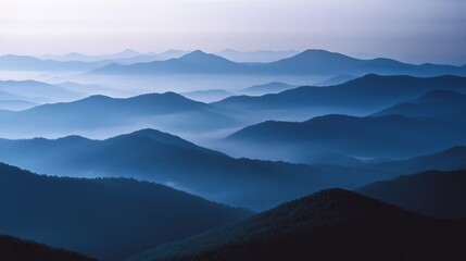 Fototapeta premium Layers of mist-covered blue mountains stretching into the horizon, creating a serene and endless landscape of tranquility.