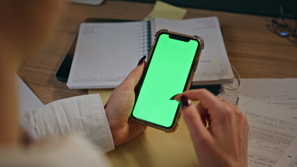 Businesswoman fingers using chromakey smartphone surfing on workplace closeup