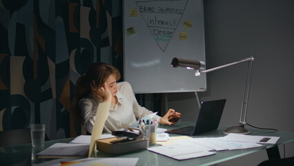 Overloaded businesswoman looking laptop at late office. Lady examining documents