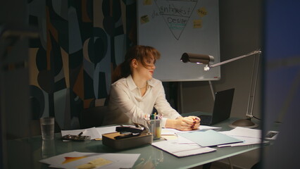 Exhausted lady having overtime work at office late night. Tired woman working